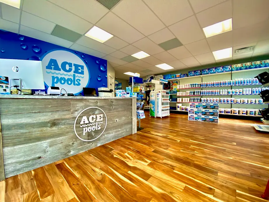 Inside the Ace Pools store: the blue Ace logo wall, a wood reception counter and shelves of pool chemicals