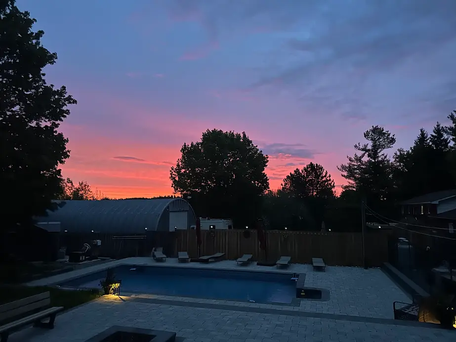 A pool under a dusk sky with low lights along the deck
