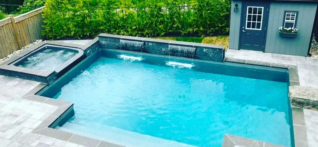 Pool with a spa and sheer descents beside a garden shed