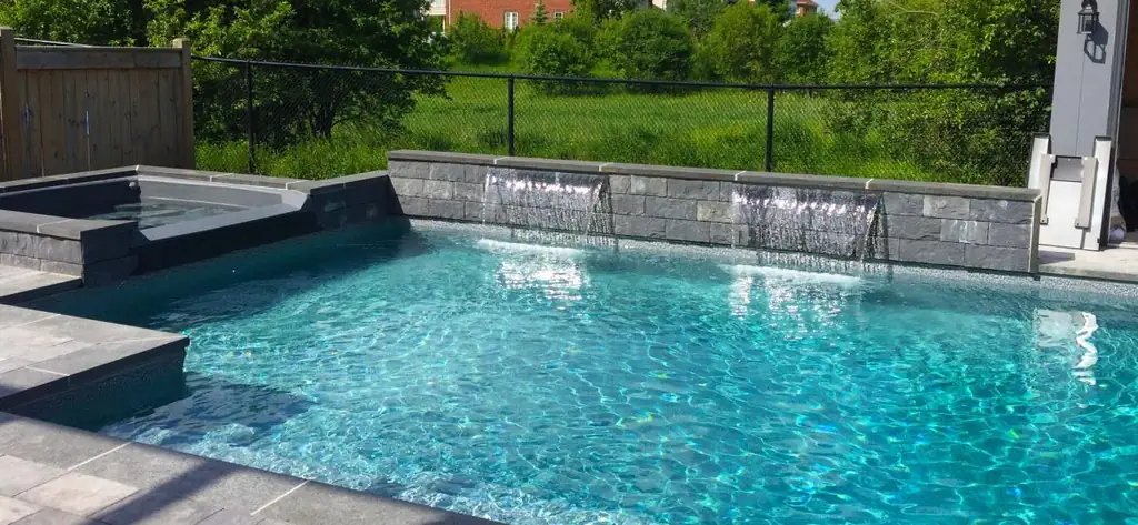 Pool with sheer descents over grey stone and a field behind