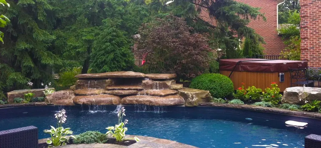 Freeform pool with a rock waterfall and a hot tub behind it