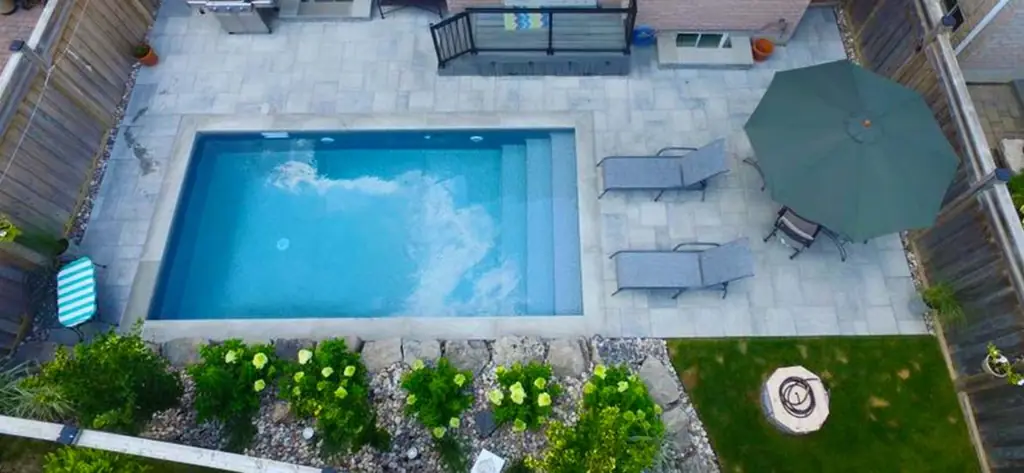 Aerial view of a small plunge pool set in an interlock patio with an umbrella and a fire pit